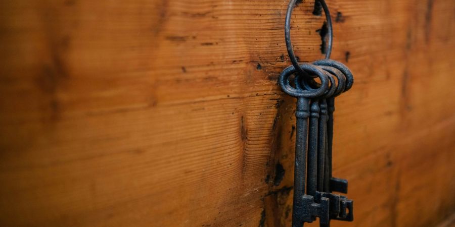 old fashio keys, hanging on a ring, attached to a wood board